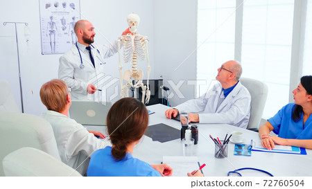 Expert radiologist demonstrating on skeleton during briefing Expert radiologist demonstrating on skeleton during briefing 72760504