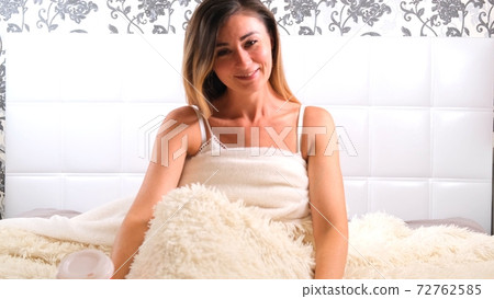 woman sits in the bed and stretches. The concept of starting a new day, enjoying the weekend, no woman sits in the bed and stretches. The concept of starting a new day, enjoying the weekend, no 72762585