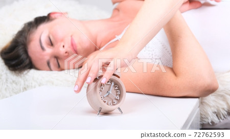 Woman sleep on the bed turns off the alarm clock wake up at the morning, Selective focus. Woman sleep on the bed turns off the alarm clock wake up at the morning, Selective focus. 72762593