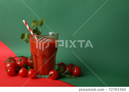Glass of tomato juice and tomatoes on two tone background Glass of tomato juice and tomatoes on two tone background 72765360