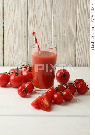 Glass with tomato juice and straw and tomatoes on wooden background Glass with tomato juice and straw and tomatoes on wooden background 72765389