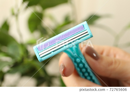 Female hand hold razor on blurred background, close up 72765606