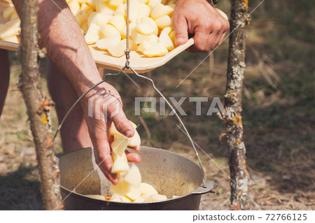 Male hands add potato in a cauldron 72766125