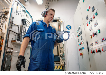 Marine engineer officer controlling vessel enginesand propulsion in engine control room ECR 72766347