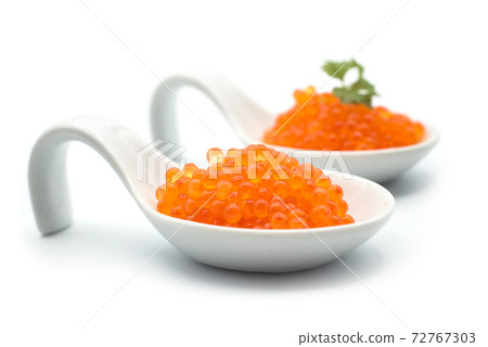 Closeup of trout eggs in a white ceramic spoon on white background 72767303