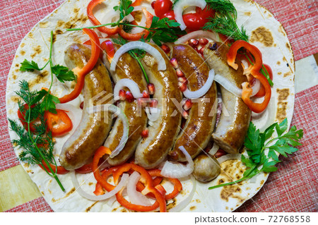 Fried pork sausages on pita bread with ketchup and Armenian appetizer Aivar with vegetables. Lavash, red bell pepper, onions, sausages. Oktoberfest food, the concept of the pub Fried pork sausages on pita bread with ketchup and Armenian appetizer Aivar with vegetables. Lavash, red bell pepper, onions, sausages. Oktoberfest food, the concept of the pub 72768558