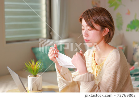 Telework_Woman taking a mask and looking at the mask Telework_Woman taking a mask and looking at the mask 72769802
