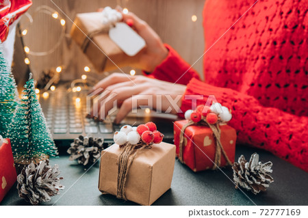 Christmas online shopping, work and education. New Year decorations on table. Woman with notebook computer at home. Winter holidays sales Christmas online shopping, work and education. New Year decorations on table. Woman with notebook computer at home. Winter holidays sales 72777169