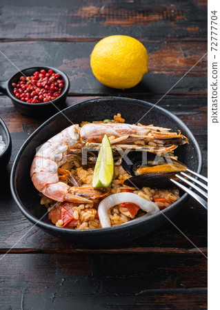 Sea food specialties paella in bowl on old dark wooden table Sea food specialties paella in bowl on old dark wooden table 72777704