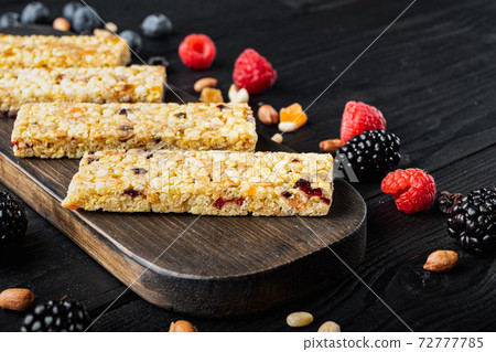 Superfood breakfast bars with oats nuts and berries with copy space, on black wooden table Superfood breakfast bars with oats nuts and berries with copy space, on black wooden table 72777785