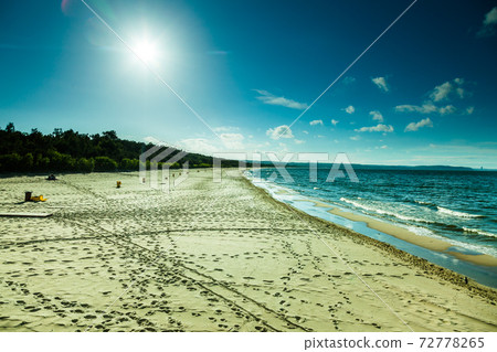 View of cloudy sky at sea with footprints on a beach 72778265