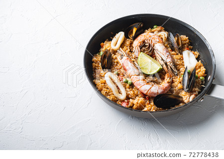 Paella with seafood and chicken on white background with space for text Paella with seafood and chicken on white background with space for text 72778438