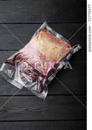 New York beef steak cut in plastic pack, on black wooden table, top view, with copy space for text 72778477
