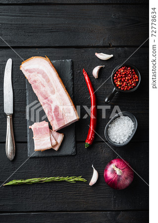Bacon pancetta cut and sliced with herbs on black wooden table, top view Bacon pancetta cut and sliced with herbs on black wooden table, top view 72778634