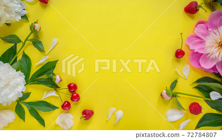 Flowers of peony, branches, leaves and petals and berries of cherry, strawberry with space for text on a yellow background. Flat lay, top view. 72784807