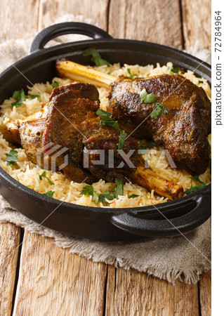 Yemeni dish of baked lamb shank served with aromatic rice close-up in a frying pan. vertical 72784964