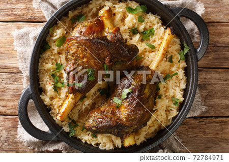 Haneeth is a slow roasted lamb dish from Yemen served on a plate of rice closeup. horizontal top view 72784971