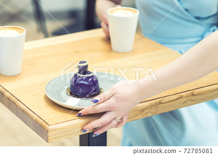 The hand of the waiter puts the piece of cake on the table at cafe. The hand of the waiter puts the piece of cake on the table at cafe. 72785081