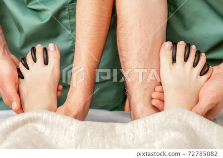 Massage stones between the toes. 72785082