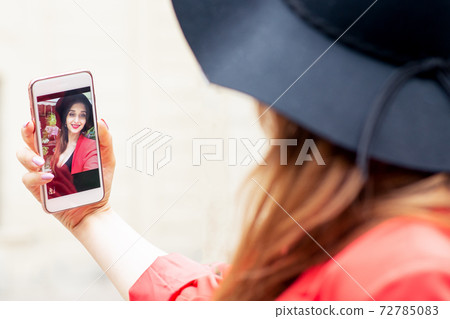 Smartphone in hand of happy woman who is making selfie. Smartphone in hand of happy woman who is making selfie. 72785083