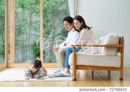 A girl lying down and drawing, and a dad and mom watching over it A girl lying down and drawing, and a dad and mom watching over it 72786032