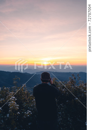 A photographer taking a picture of the sunset A photographer taking a picture of the sunset 72787004