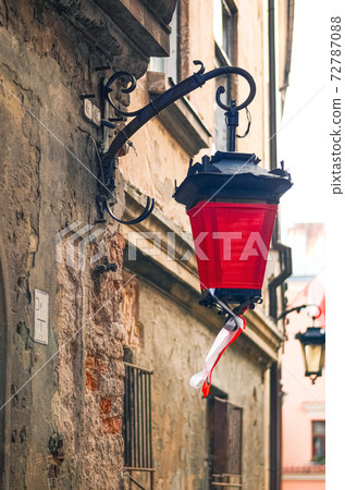 Fragment of an ancient wall with an old street lamp with red cloth and ribbons with national Polish colors in Lublin, Poland Fragment of an ancient wall with an old street lamp with red cloth and ribbons with national Polish colors in Lublin, Poland 72787088