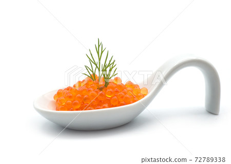 Closeup of trout roe in a ceramic spoon with a dill leaf on white background 72789338