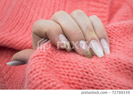 Closeup of hand of woman with beautiful nails in pink pullover background 72789339