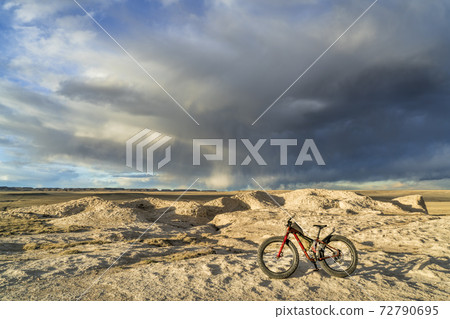 fat bike in badlands with storm clouds 72790695