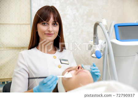 Cosmetology specialist applying a facial mask to face using brush. Beauty treatment. Skincare. 72790937