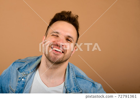 Handsome man standing and smiling isolated on light brown studio background. Handsome man standing and smiling isolated on light brown studio background. 72791361