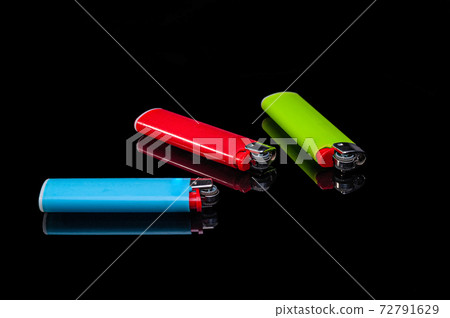 blue, green and red plastic gas lighters on an isolated black background with reflection blue, green and red plastic gas lighters on an isolated black background with reflection 72791629