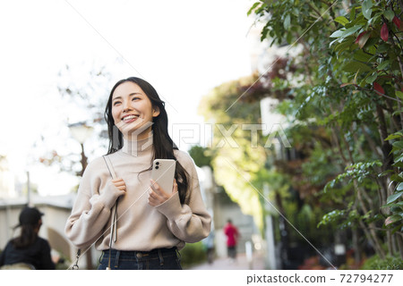 A young woman walking with a smartphone A young woman walking with a smartphone 72794277