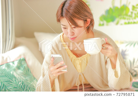 女人拿著一杯咖啡,看著smartphone_Close-up 女人拿著一杯咖啡,看著smartphone_Close-up 72795871