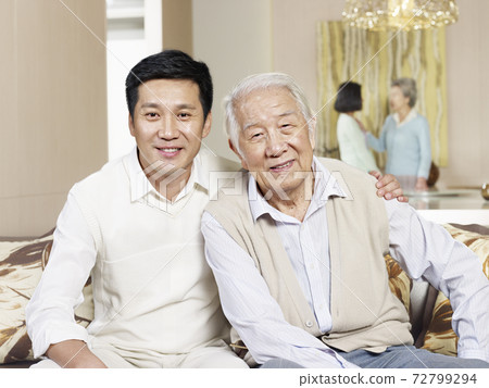 portrait of senior father and adult son sitting on couch at home portrait of senior father and adult son sitting on couch at home 72799294