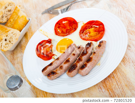 Breakfast of fried eggs with sausage and tomatoes 72801520