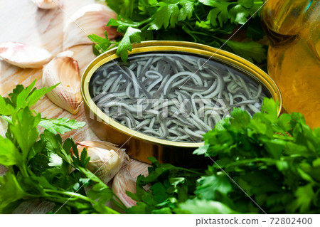 Pickled eels on background with garlic and greens at table 72802400
