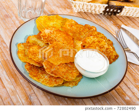 Draniki with sour cream at plate, dish of Belarusian cuisine Draniki with sour cream at plate, dish of Belarusian cuisine 72802490