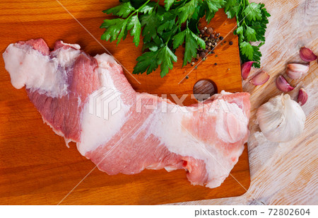 Preparation of raw pork cinch parsley and garlic on cutting board 72802604