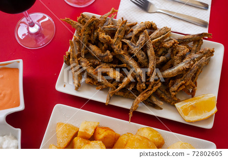 Fried anchovies served with slice of lemon Fried anchovies served with slice of lemon 72802605