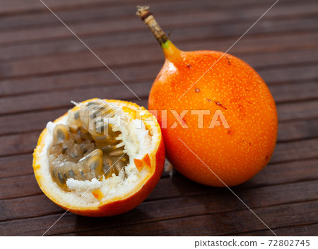 Whole and half fruits fresh granadilla on wooden table 72802745