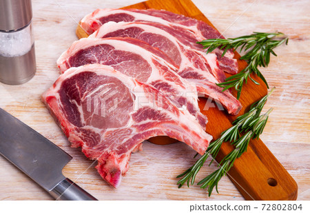 Raw pork's chops and rosemary on wooden surface Raw pork's chops and rosemary on wooden surface 72802804