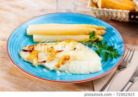 Deliciously roasted halibut fillet with asparagus and greens 72802925