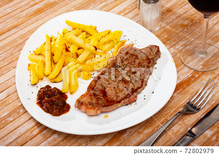 Veal entrecote with French fries and caramelized onion Veal entrecote with French fries and caramelized onion 72802979