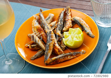 Fried anchovies served with slice of lemon Fried anchovies served with slice of lemon 72802980