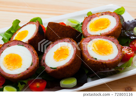 Tasty scotch eggs served with greens, leek and tomatoes at plate Tasty scotch eggs served with greens, leek and tomatoes at plate 72803116