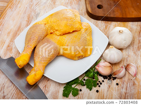 Raw chicken leg quarters with garlic, greens and spices 72803408