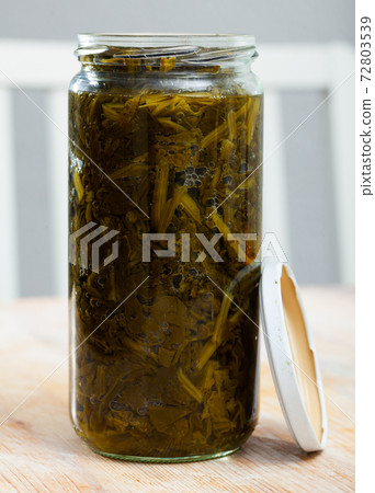 Canned green spinach in open glass jar on wooden surface Canned green spinach in open glass jar on wooden surface 72803539