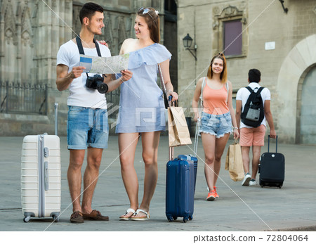 smiling travelers holding map in hands and looking for their way in european town smiling travelers holding map in hands and looking for their way in european town 72804064